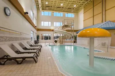 a pool with chairs and a slide in a building at Best Western Sunrise Inn & Suites in Stony Plain