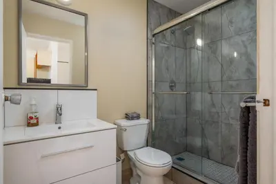 a bathroom with a toilet and a glass shower at Croft Inn Motel in Crofton