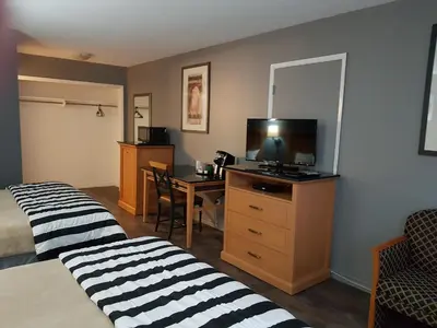 a hotel room with two beds and a desk with a television at Metro Inn in Victoria