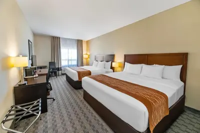 a hotel room with two beds and a desk at Comfort Inn in Dawson Creek