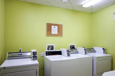 a laundry room with three washes and a green wall at Comfort Inn in Dawson Creek
