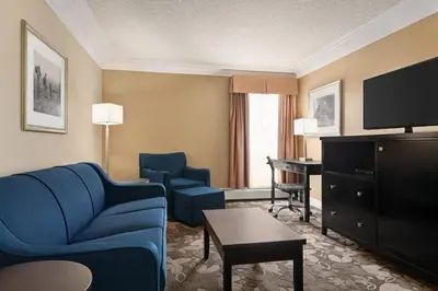 a hotel room with a blue couch and chairs and a television at Nova Inn Yellowknife in Yellowknife