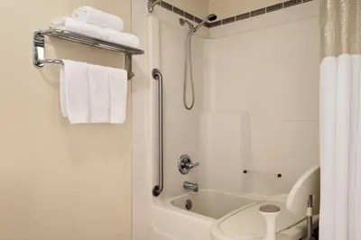 a white bathroom with a toilet and a shower at Nova Inn Yellowknife in Yellowknife