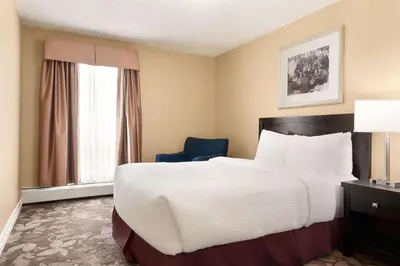 a hotel room with a large bed and a blue chair at Nova Inn Yellowknife in Yellowknife