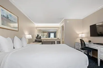a hotel room with a white bed and a desk at Glenwood Inn & Suites in Trail