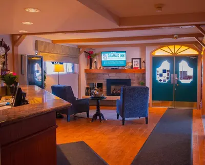 a lobby with a bar and chairs and a fireplace at Grama's Inn in Prince George