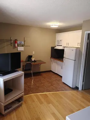 a kitchen with a white refrigerator and a table at Magnuson Hotel Creston in Creston