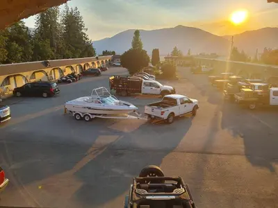 a group of vehicles parked in a parking lot with a boat at Magnuson Hotel Creston in Creston