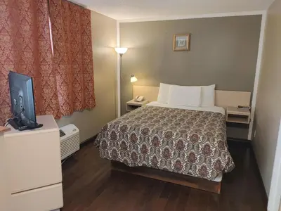 a hotel room with a bed and a flat screen tv at Magnuson Hotel Creston in Creston