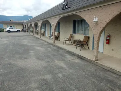 a building with chairs and a car parked in a parking lot at Magnuson Hotel Creston in Creston