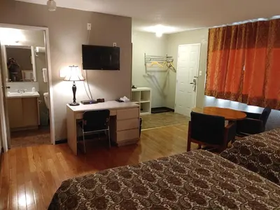 a hotel room with a bed and a desk and a table at Magnuson Hotel Creston in Creston