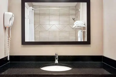 a bathroom with a sink with a phone and a mirror at Days Inn by Wyndham Sylvan Lake in Sylvan Lake