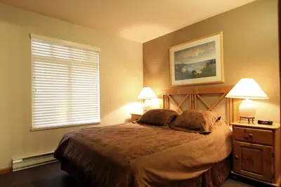a bedroom with a bed with two lamps and a window at Sunpath Condos by Whistler Retreats in Whistler