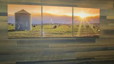 a wall with a picture of a silo in a field at Days Inn & Suites by Wyndham Brooks in Brooks