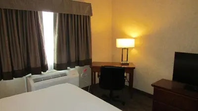 a hotel room with a bed and a desk and a window at Days Inn & Suites by Wyndham Brooks in Brooks