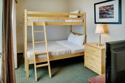 a bunk bed with a ladder next to a desk at Lakeview Inns & Suites - Slave Lake in Slave Lake