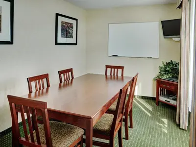 a conference room with a table and chairs and a screen at Lakeview Inns & Suites - Slave Lake in Slave Lake