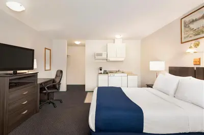 a hotel room with a bed and a desk and a television at Travelodge by Wyndham McBride in McBride