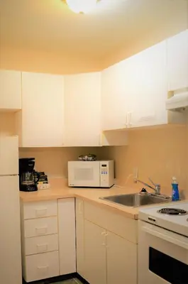 a kitchen with white cabinets and a sink and a microwave at Travelodge by Wyndham McBride in McBride