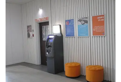 an atm machine in a building with two orange stools at Motel 6 Kerrobert, SK in Kerrobert