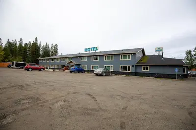 a large blue building with cars parked in a parking lot at Northway Motor Inn in Dease Lake