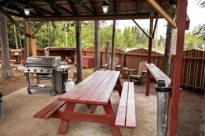 a picnic table and a grill under a pavilion at Northway Motor Inn in Dease Lake