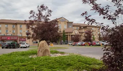 a tree stump sitting in the grass in front of a building at Pomeroy Hotel Fort St. John in Fort Saint John