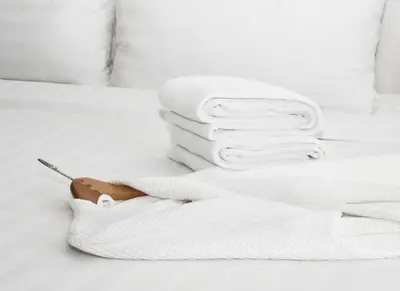 a white bed with a pile of towels on it at Pomeroy Inn and Suites Chetwynd in Chetwynd