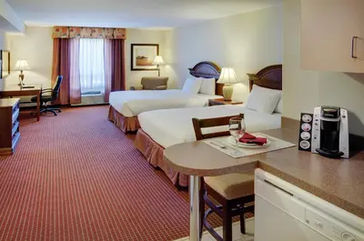 a hotel room with two beds and a desk at Pomeroy Inn and Suites Chetwynd in Chetwynd
