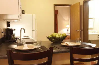 a kitchen with a table with a bowl of apples on it at Pomeroy Inn & Suites Fort St. John in Fort Saint John