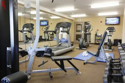 a gym with several tread machines and mirrors at Pomeroy Inn & Suites Fort St. John in Fort Saint John