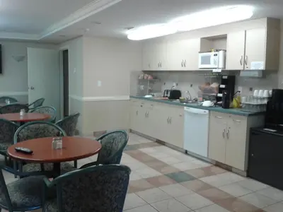 a kitchen and dining room with tables and chairs at Stampeder Inn in Ponoka