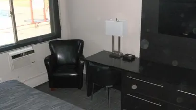 a bedroom with a bed and a desk and a chair at Stampeder Inn in Ponoka