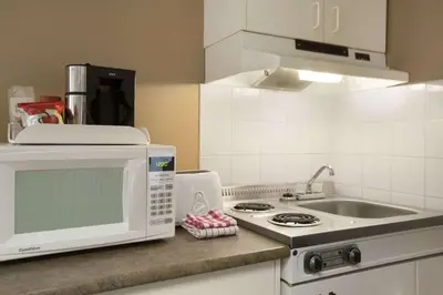 a kitchen with a microwave oven and a sink at Central Suite Hotel in Lloydminster