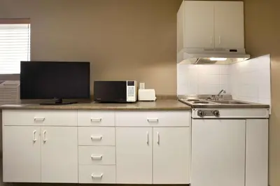 a kitchen with white cabinets and a sink and a microwave at Central Suite Hotel in Lloydminster