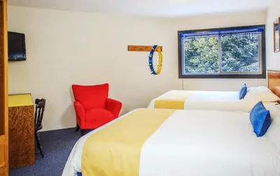 a hotel room with two beds and a red chair at The Bulldog Hotel in Silver Star