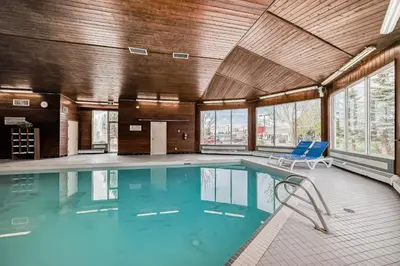a swimming pool in a building with blue chairs at Stony Plain Inn & Suites in Stony Plain
