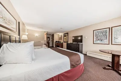 a hotel room with a large bed and a table at Stony Plain Inn & Suites in Stony Plain