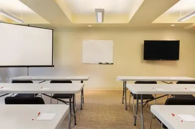 an empty classroom with tables and a flat screen tv at Ramada by Wyndham Nanaimo in Nanaimo
