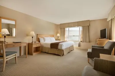 a hotel room with a bed and a desk and a television at Ramada by Wyndham Nanaimo in Nanaimo