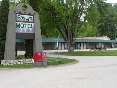 a motel sign with a bench in front of a building at Ray Lyn Motel in Trail