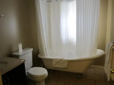 a bathroom with a tub and a toilet and a window at Reynolds Hotel in Lillooet