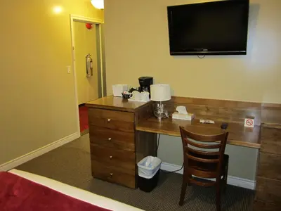 a hotel room with a desk with a television on the wall at Reynolds Hotel in Lillooet