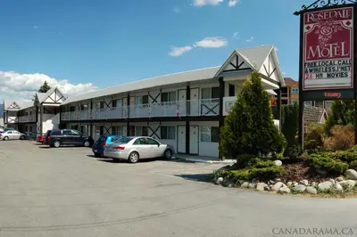 a motel with cars parked in a parking lot at Rosedale Motel in Summerland