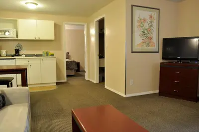 a living room with a couch and a tv and a kitchen at Rosedale Motel in Summerland
