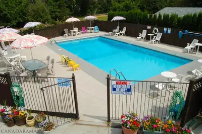 a swimming pool with umbrellas and tables and chairs at Rosedale Motel in Summerland