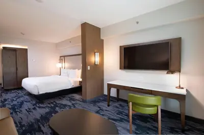 a hotel room with a bed and a desk with a television at Fairfield by Marriott Edmonton International Airport in Edmonton