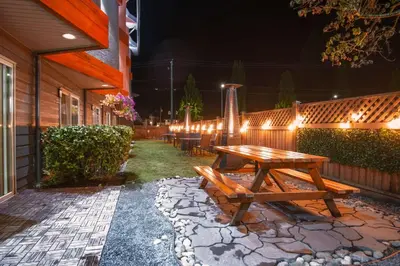 a wooden picnic table next to a fence with lights at Coast Parksville Hotel in Parksville