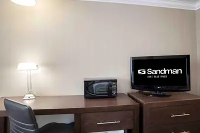a room with a desk with a television and a computer on it at Sandman Inn Blue River in Blue River