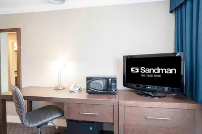 a room with a desk with a television and a printer at Sandman Inn Blue River in Blue River